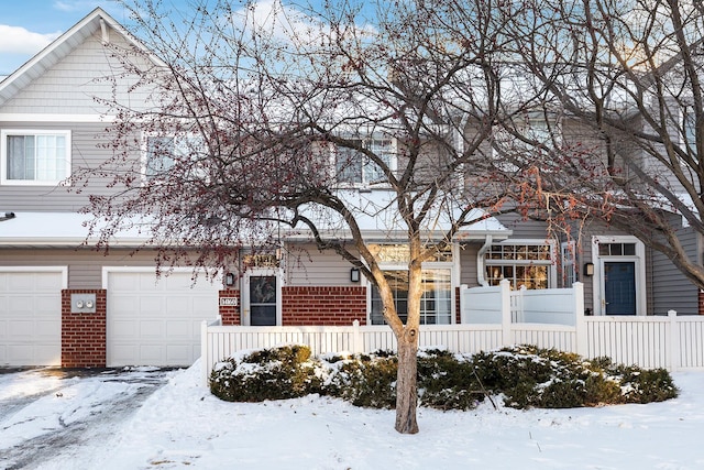 view of front of property with a fenced front yard, brick siding, and a garage