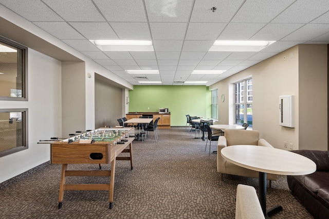 recreation room featuring a drop ceiling and dark colored carpet