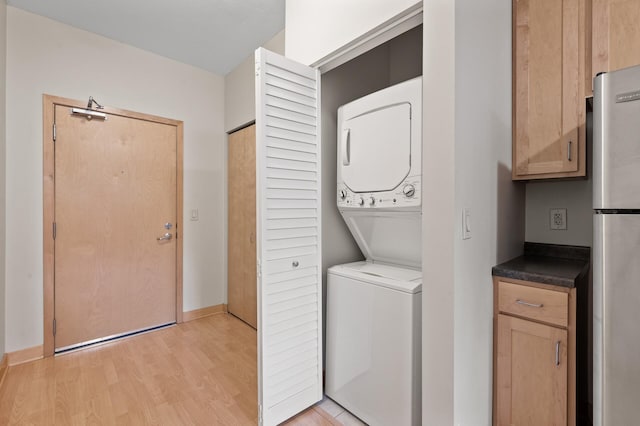 laundry room with light wood-type flooring and stacked washing maching and dryer