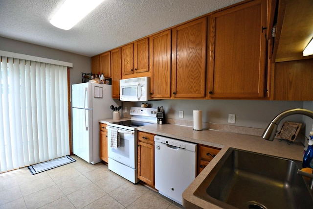 kitchen featuring white appliances, sink, light tile patterned floors, and a textured ceiling