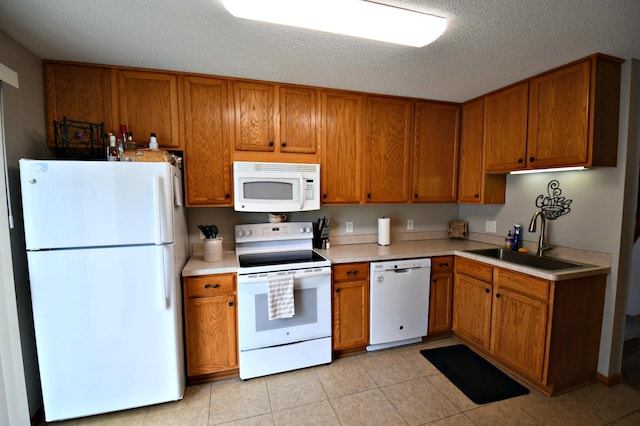 kitchen with light tile patterned flooring, white appliances, sink, and a textured ceiling