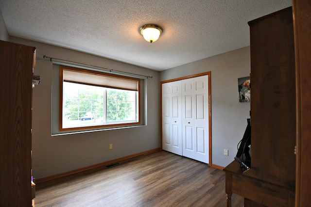 unfurnished bedroom with a closet, hardwood / wood-style flooring, and a textured ceiling