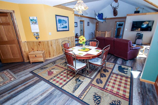 dining room with dark wood-type flooring, wood walls, vaulted ceiling, and a notable chandelier