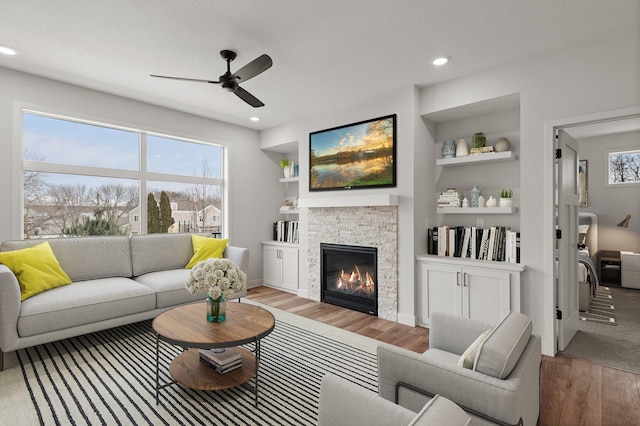 living room with hardwood / wood-style flooring, a wealth of natural light, a fireplace, and built in shelves