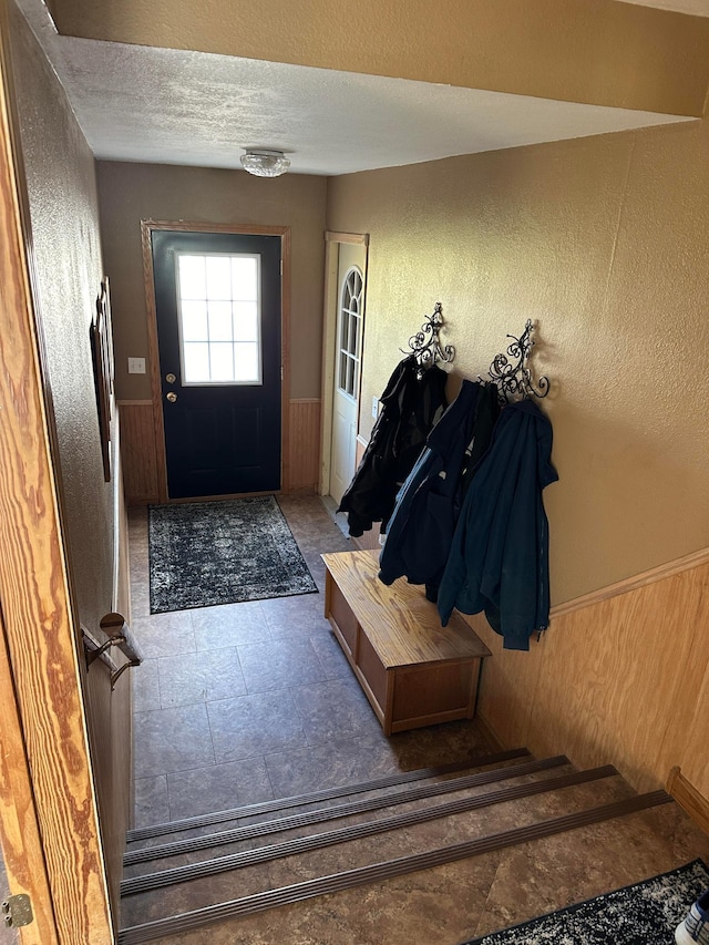 foyer featuring wood walls and a textured ceiling