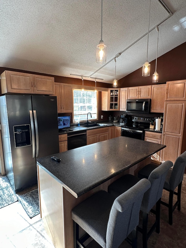 kitchen featuring pendant lighting, lofted ceiling, sink, and black appliances