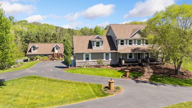shingle-style home featuring driveway, a front yard, and a porch