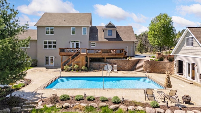 swimming pool with stairway, french doors, a wooden deck, and a patio