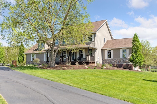 view of front facade with covered porch, stone siding, and a front lawn