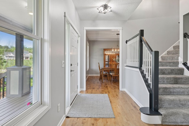 entrance foyer with light wood-style flooring, stairway, a chandelier, and baseboards