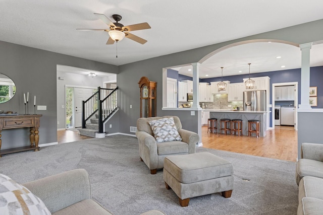 living area featuring ornate columns, ceiling fan, stairway, washing machine and dryer, and recessed lighting