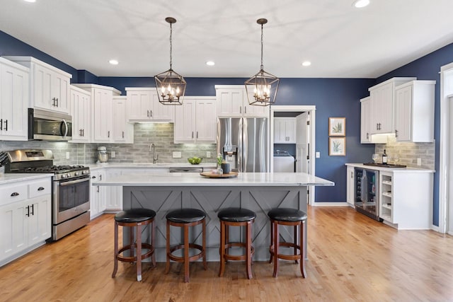 kitchen featuring appliances with stainless steel finishes, beverage cooler, a sink, washer / dryer, and light countertops