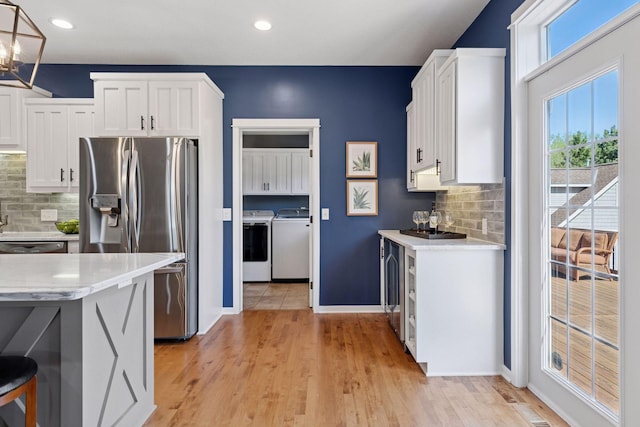 kitchen featuring stainless steel fridge with ice dispenser, washing machine and clothes dryer, wine cooler, white cabinetry, and recessed lighting