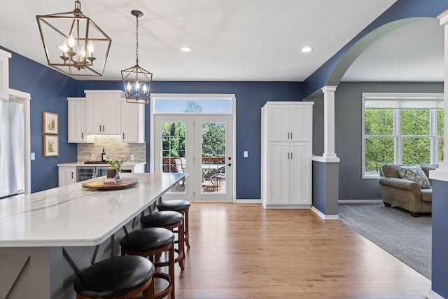 dining room with a chandelier, light wood-style floors, arched walkways, decorative columns, and recessed lighting