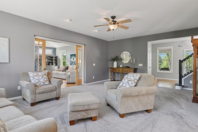 living area with light carpet, a ceiling fan, and healthy amount of natural light