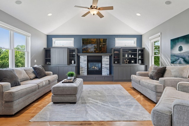living room with lofted ceiling, ceiling fan, a fireplace, light wood-type flooring, and recessed lighting