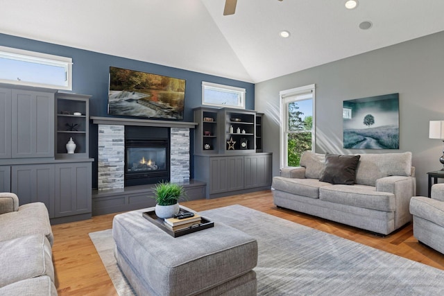 living room featuring vaulted ceiling, a fireplace, light wood-type flooring, ceiling fan, and recessed lighting