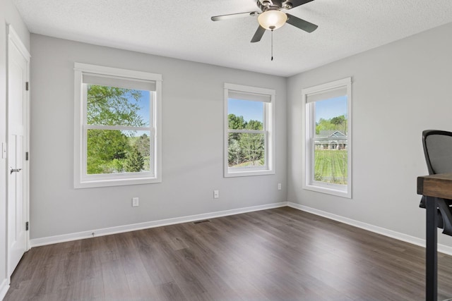 unfurnished bedroom featuring dark wood-type flooring, multiple windows, a textured ceiling, baseboards, and ceiling fan