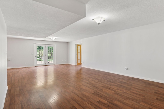 spare room with a textured ceiling, wood finished floors, and baseboards