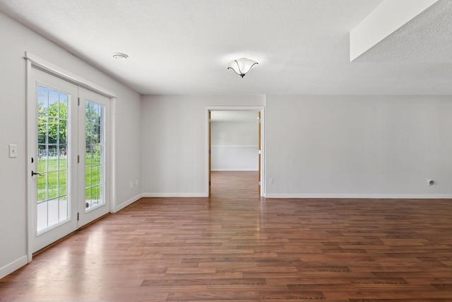 empty room with wood finished floors, baseboards, and a textured ceiling