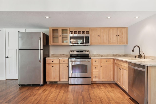 kitchen with stainless steel appliances, light brown cabinets, a sink, light wood-type flooring, and recessed lighting