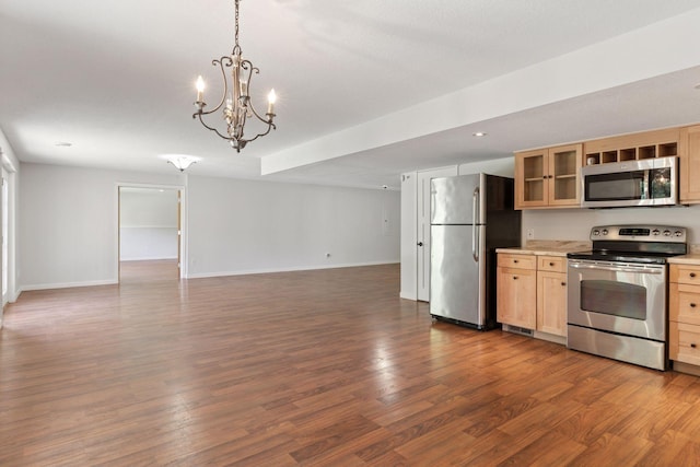 kitchen featuring stainless steel appliances, light brown cabinets, open floor plan, light countertops, and wood finished floors