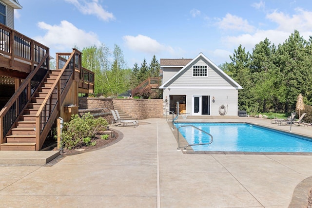 view of pool with stairway, a patio area, a deck, and an outbuilding