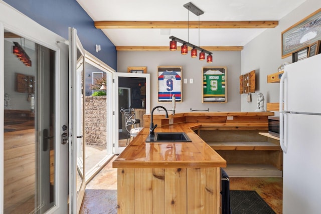 kitchen with freestanding refrigerator, butcher block counters, a sink, beam ceiling, and stainless steel microwave