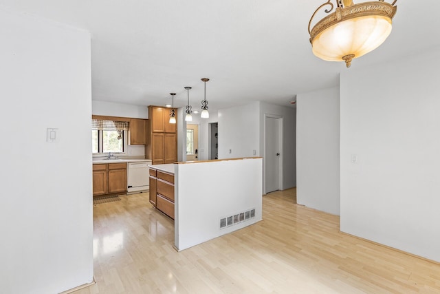 kitchen with light wood-type flooring, a kitchen island, sink, pendant lighting, and white dishwasher