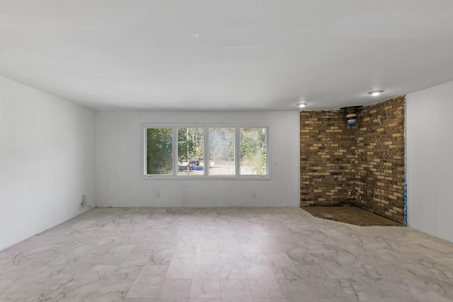 unfurnished room featuring brick wall