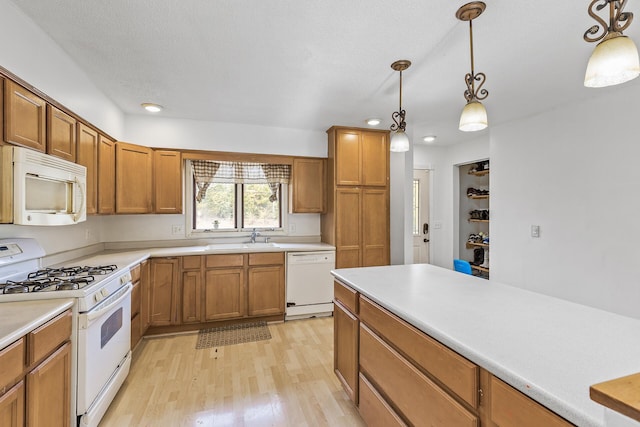 kitchen featuring white appliances, light hardwood / wood-style floors, decorative light fixtures, and sink