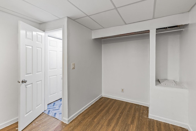 basement with a drop ceiling and dark hardwood / wood-style floors