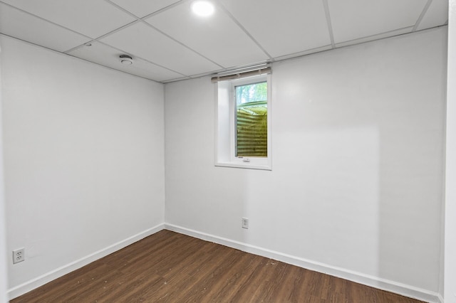 empty room with a drop ceiling and dark wood-type flooring