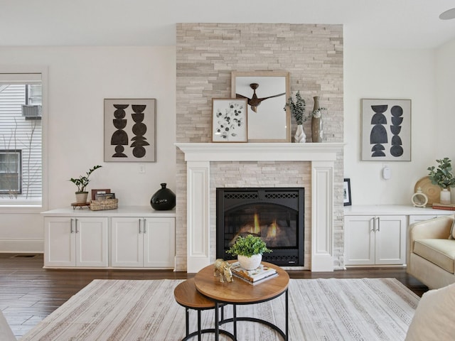 living area with visible vents, a fireplace, dark wood-type flooring, and baseboards