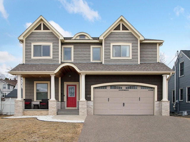 craftsman inspired home featuring aphalt driveway, a porch, an attached garage, and a shingled roof