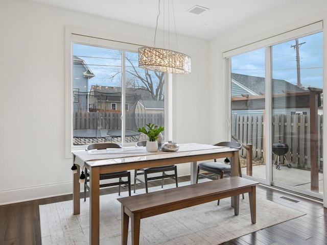 dining area featuring visible vents, baseboards, and wood finished floors