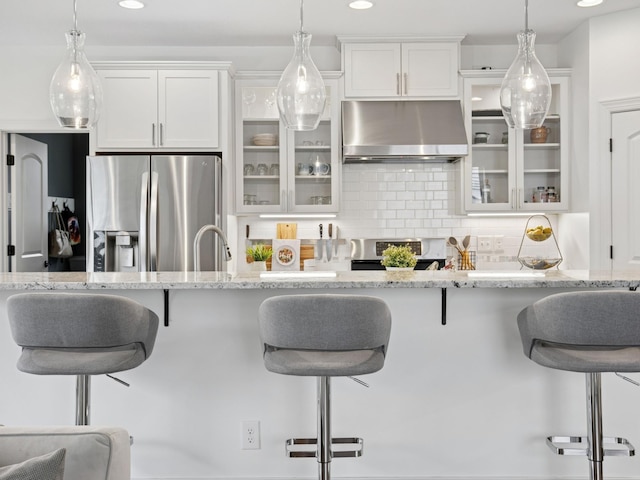 kitchen with ventilation hood, stainless steel fridge, a breakfast bar area, decorative backsplash, and range