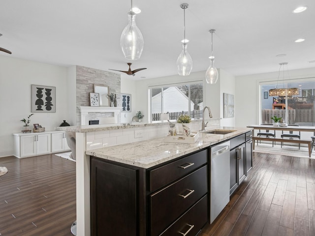 kitchen with ceiling fan, dark wood finished floors, open floor plan, stainless steel dishwasher, and a sink