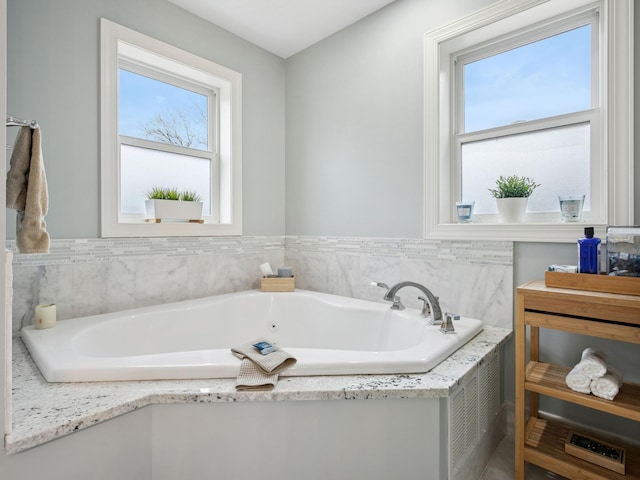 bathroom with a garden tub and a healthy amount of sunlight