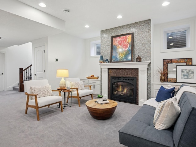 living room featuring light carpet, recessed lighting, stairs, and a large fireplace