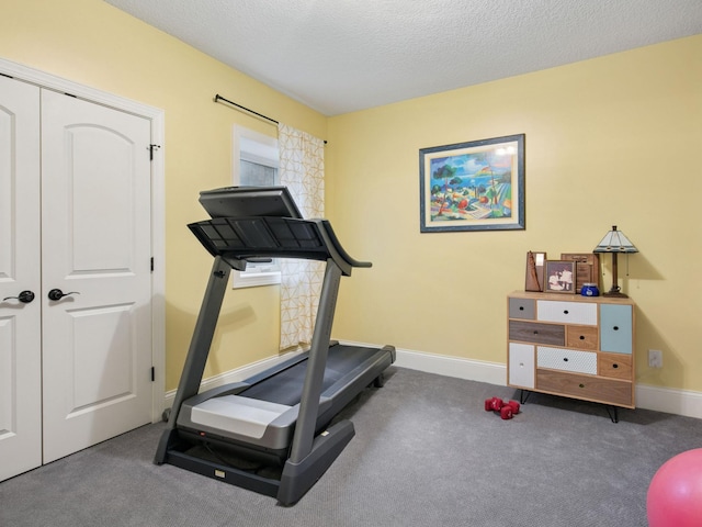 workout room with baseboards, carpet floors, and a textured ceiling