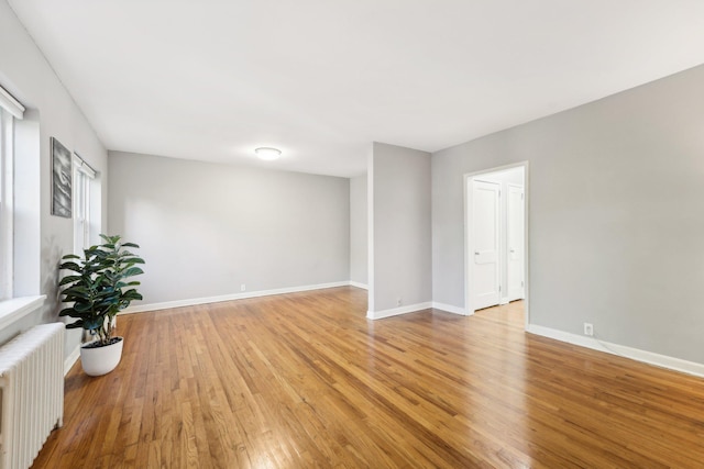 spare room with radiator heating unit and light wood-type flooring