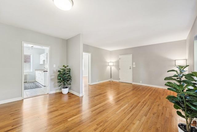 spare room featuring radiator heating unit and light hardwood / wood-style floors