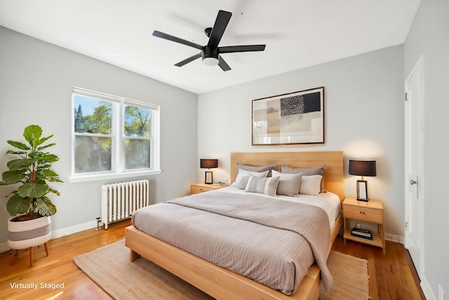 bedroom with radiator heating unit, hardwood / wood-style flooring, and ceiling fan