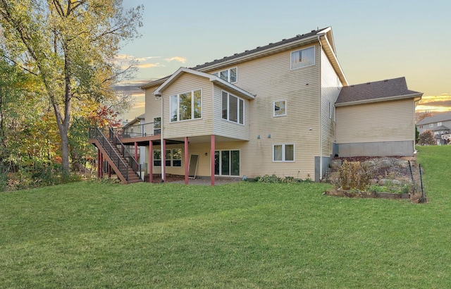 back house at dusk with a lawn and a deck