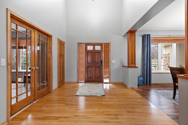 foyer entrance with french doors, light hardwood / wood-style floors, and ornate columns