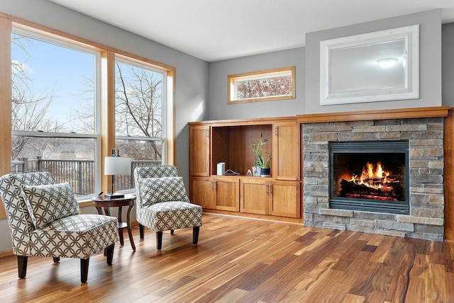 living area with light hardwood / wood-style floors and a stone fireplace