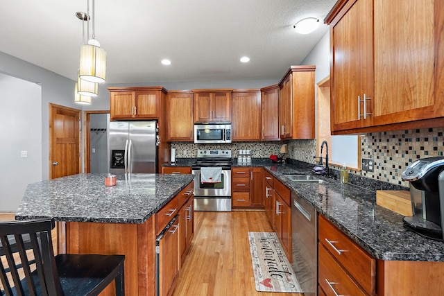 kitchen featuring sink, a center island, pendant lighting, light hardwood / wood-style floors, and appliances with stainless steel finishes