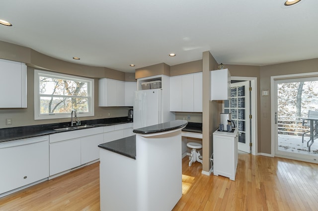 kitchen featuring sink, a kitchen island, white cabinetry, light hardwood / wood-style flooring, and white refrigerator