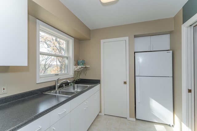 kitchen featuring white fridge, light tile patterned floors, white cabinetry, and sink